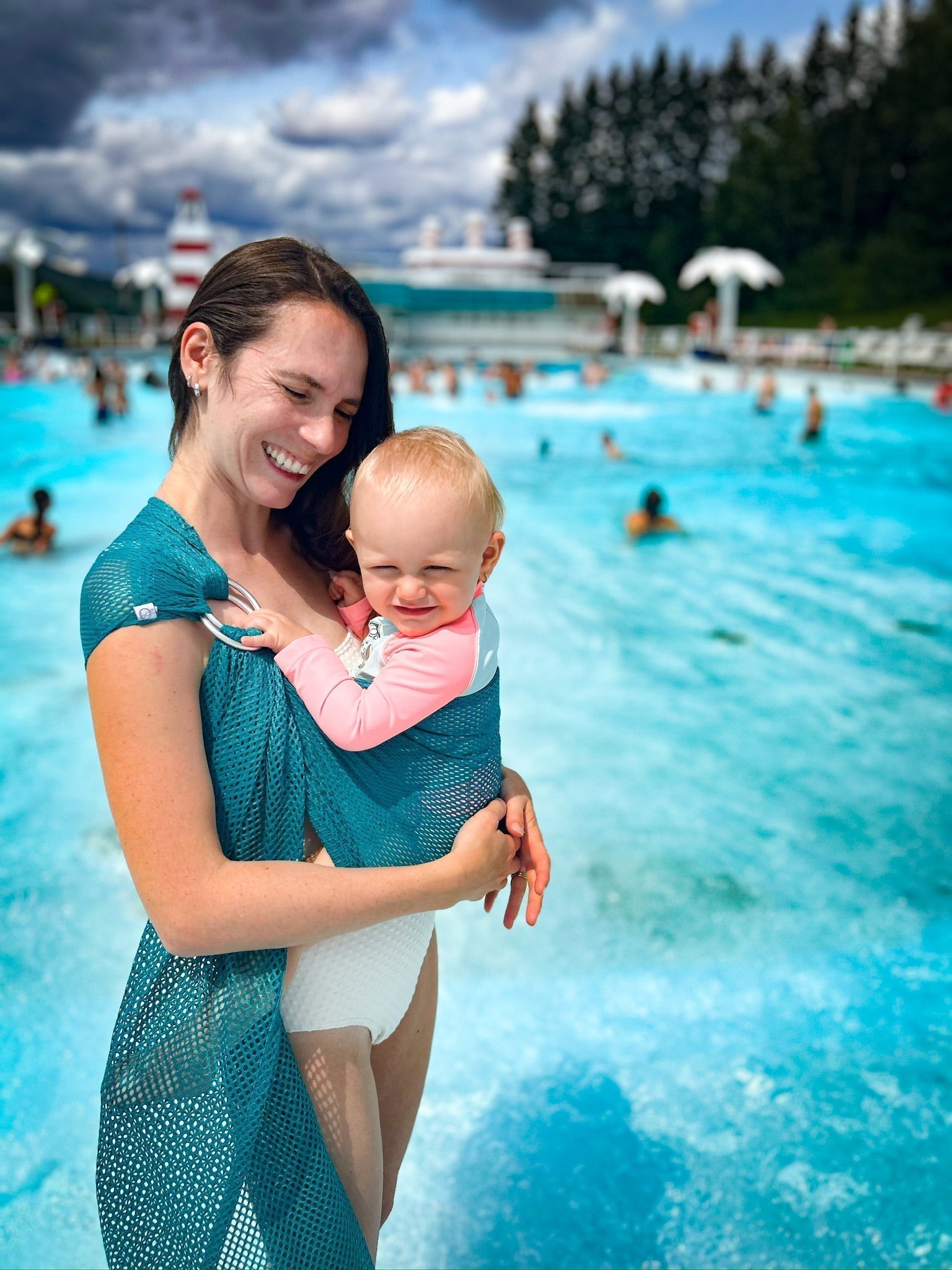 Parent portant bébé dans l’eau avec un porte-bébé Chimpäroo en été – portage aquatique plage